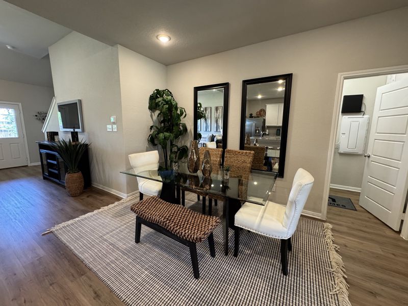 A chic dining area with a glass table, wicker and upholstered chairs, large mirrors, and a cozy rug for a modern touch.