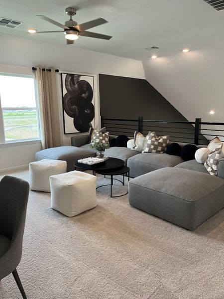 A cozy living space featuring plush gray seating, abstract art, and modern accents, perfect for relaxation and style.