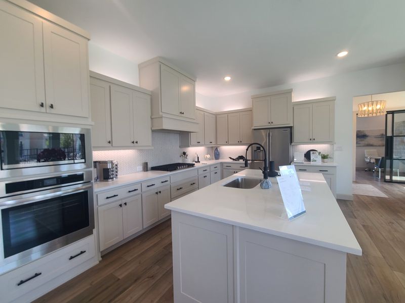 A modern kitchen with sleek cabinetry, stainless steel appliances, and a spacious island with a built-in sink.