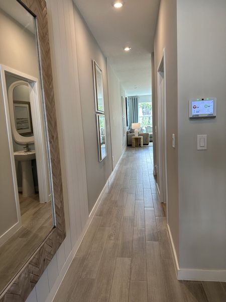 A modern hallway featuring light wood flooring, sleek walls, and stylish decor, leading to a bright living space.
