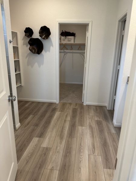 A modern hallway with wood flooring, abstract wall decor, and a spacious closet with open shelving. A modern hallway with wood flooring, abstract wall decor, and a spacious closet with open shelving.