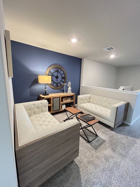 A cozy lounge area with tufted sofas, a blue accent wall, and a rustic clock, ideal for relaxation and style. A cozy lounge area with tufted sofas, a blue accent wall, and a rustic clock, ideal for relaxation and style.
