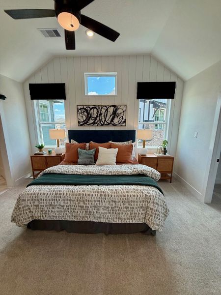 A cozy bedroom with vaulted ceilings, modern fan, abstract art, and serene decor. A cozy bedroom with vaulted ceilings, modern fan, abstract art, and serene decor.