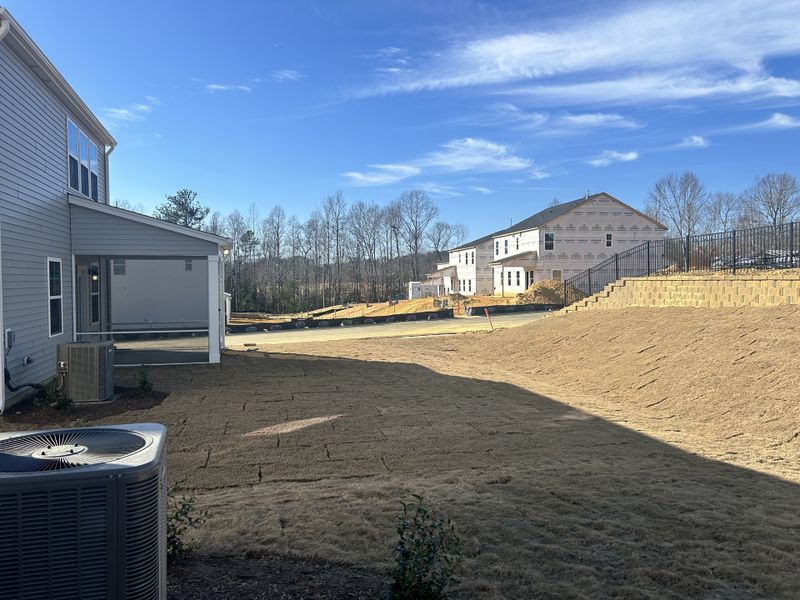 A spacious backyard with fresh landscaping and a covered patio, ideal for relaxing in Sherri Downs by Lennar (Angier, NC).