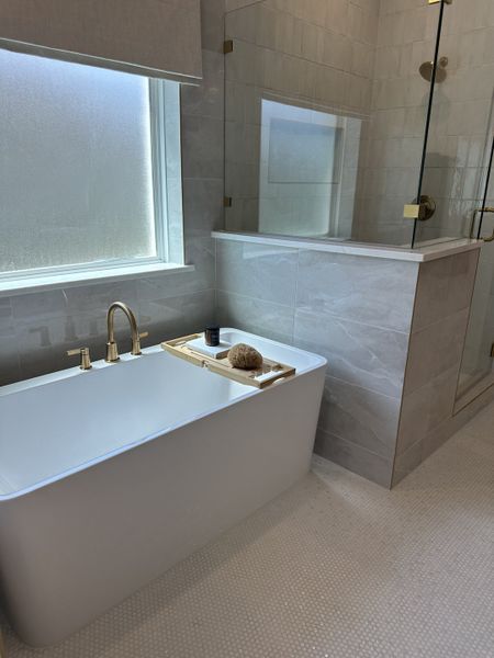 A modern bathroom featuring a sleek bathtub, glass shower enclosure, and elegant tiling. A modern bathroom featuring a sleek bathtub, glass shower enclosure, and elegant tiling.