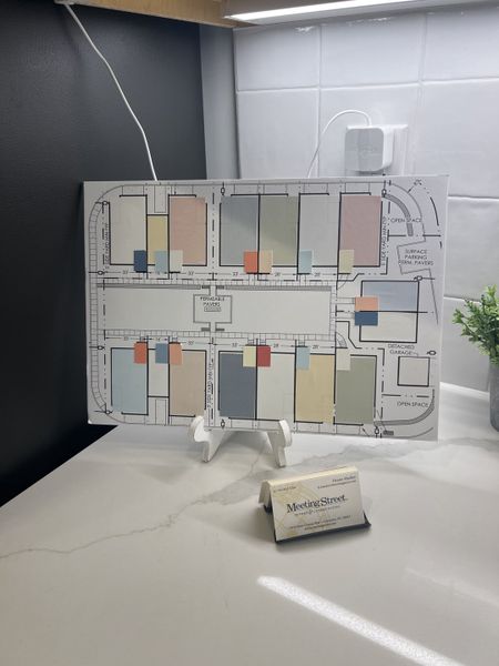 A sleek office setting with a modern countertop, displaying a detailed site plan on an easel and elegant business cards.