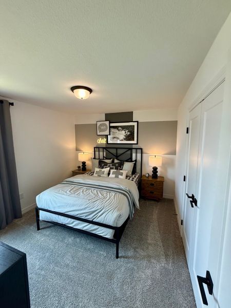 A cozy bedroom with modern decor, plush carpet, and stylish black and white accents.