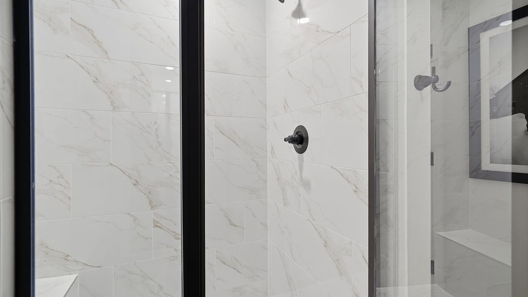 Sophisticated primary bathroom with expansive walk-in shower and polished hardware by DRB Homes