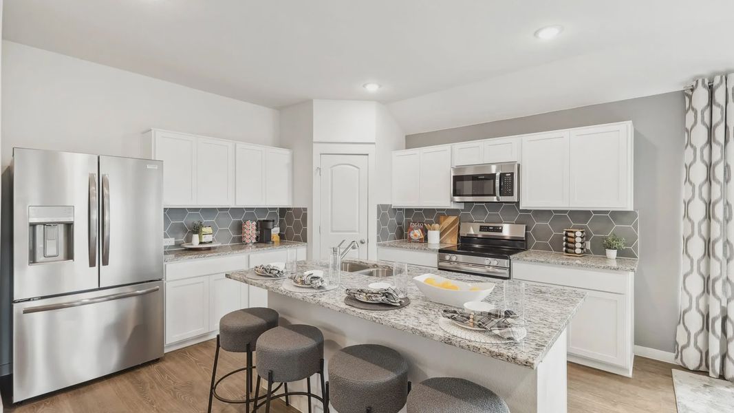 Luxurious kitchen features granite surfaces, sleek hex tile backsplash, and stainless steel appliances in Still Water Lake Estates.