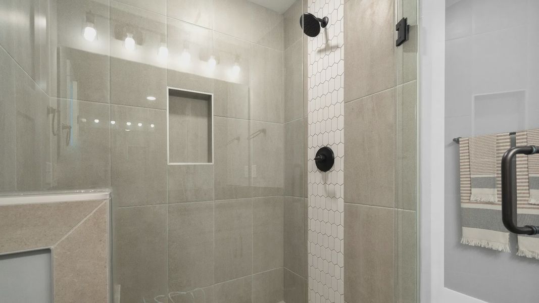 Frameless tiled walk-in shower in luxe en suite primary bathroom at Barton Hollow by DRB Homes in Fountain Inn, SC