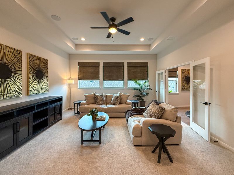 A cozy living room featuring plush seating, stylish decor, large windows, and a ceiling fan for comfort and style.