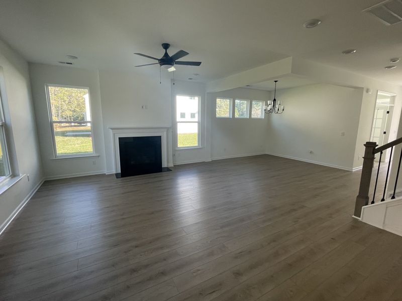A spacious living area with light wood flooring, a cozy fireplace, and elegant lighting fixtures.