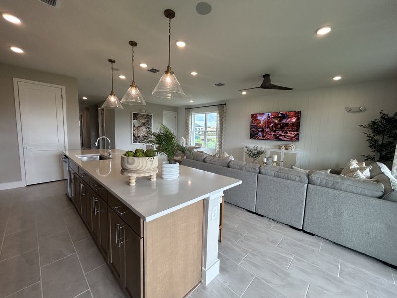 A modern open-concept living area with a large island, cozy seating, and stylish pendant lights.