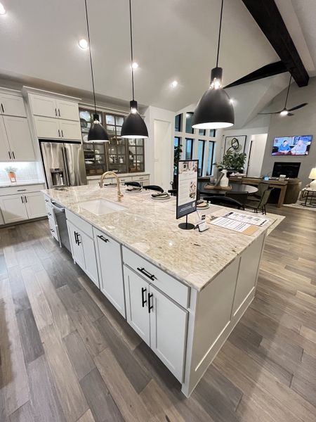 A modern kitchen featuring a large marble island, elegant pendant lights, and sleek cabinetry for a contemporary look.