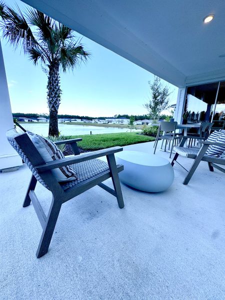 A serene patio with cozy seating and a view of a tranquil lake, surrounded by greenery and a scenic landscape.