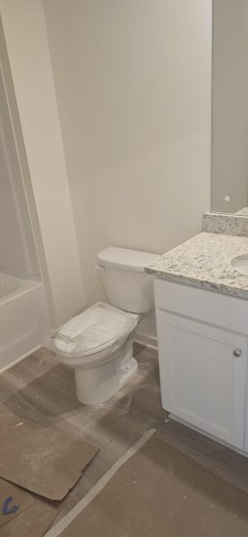 A modern bathroom featuring a polished granite countertop, white cabinetry, and sleek fixtures.
