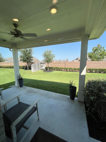 A cozy covered patio with seating, ceiling fan, and a lush backyard view. Perfect for relaxation and outdoor enjoyment.