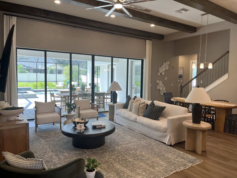 A spacious living room with floor-to-ceiling windows, cozy seating, and modern decor opens to a lush outdoor view.