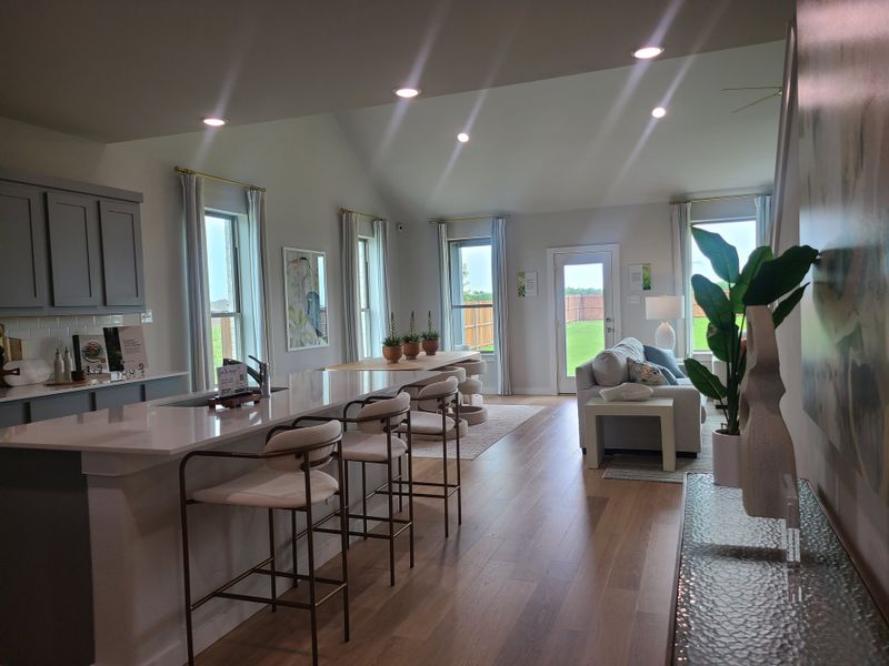 An open living space with sleek kitchen, elegant bar seating, and cozy lounge area, filled with natural light.