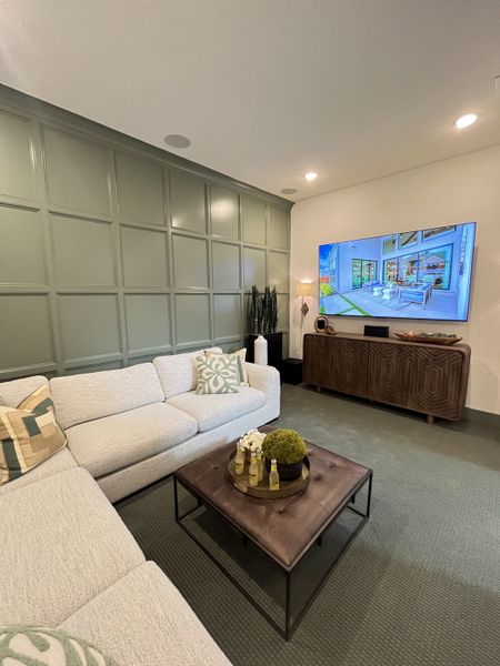 A cozy living room with an L-shaped sofa, paneled accent wall, and a wall-mounted TV for stylish entertainment.