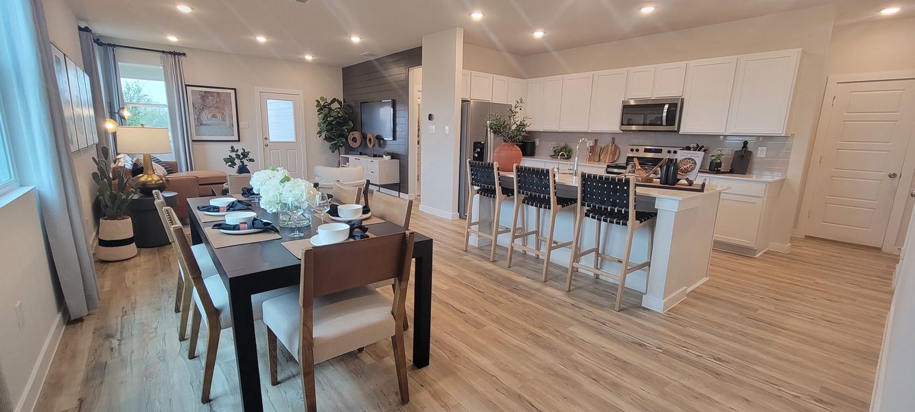 A modern open-concept living area with sleek kitchen, stylish dining, and cozy seating, featuring warm wood floors.