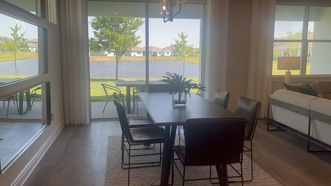 A serene dining area with a table, plush chairs, and a stunning view of the lake through large sliding glass doors.