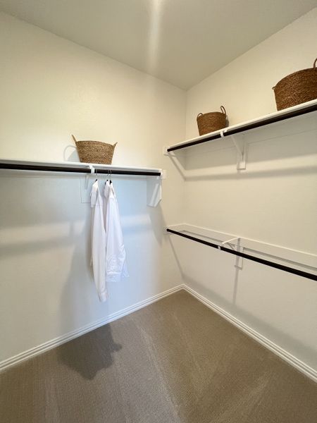 A spacious walk-in closet with built-in shelves, hanging rods, and organized wicker baskets for storage.