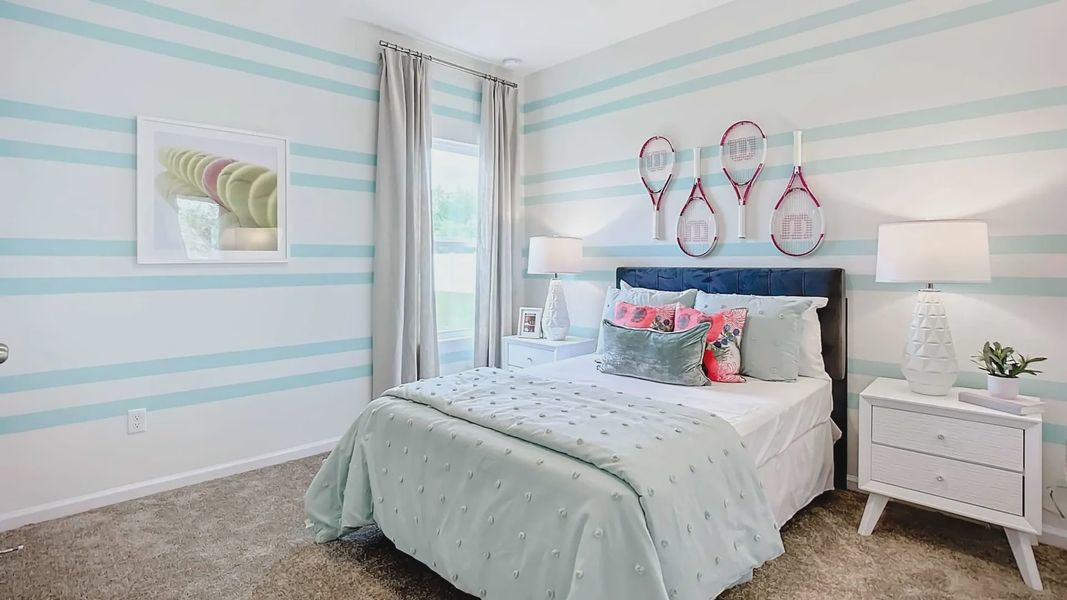 Elegant blue-striped walls and chic tennis theme elevate this Panther Creek bedroom in Jacksonville.