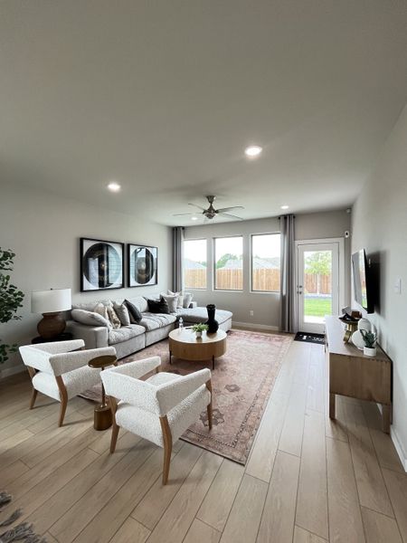 A cozy living room featuring a plush sectional sofa, stylish armchairs, a large window, and elegant decor elements.