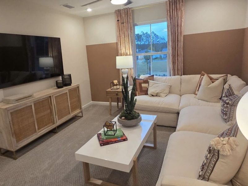 A cozy living room featuring a plush sectional sofa, sleek TV, and warm decor with natural lighting.