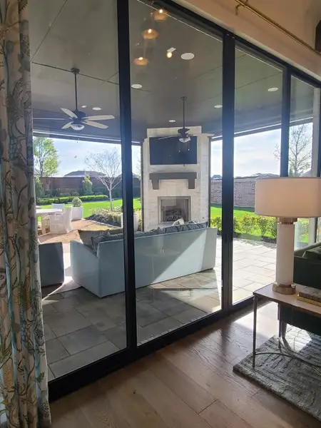 A chic outdoor living space with cozy seating, fireplace, and expansive glass doors opening to a lush backyard. A chic outdoor living space with cozy seating, fireplace, and expansive glass doors opening to a lush backyard.