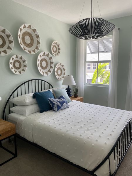 A serene bedroom with artistic wall decor, modern pendant light, and cozy bedding.