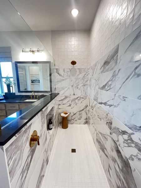 Elegant shower with marble-patterned tiles, a sleek black vanity, and gold fixtures offering a luxurious bathroom experience. Elegant shower with marble-patterned tiles, a sleek black vanity, and gold fixtures offering a luxurious bathroom experience.