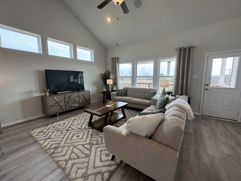 A spacious living room with vaulted ceilings, modern furnishings, large windows, and elegant decor.