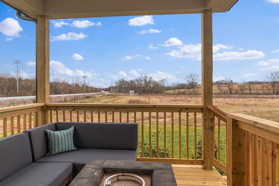A deck with a view of a field and trees. A deck with a view of a field and trees.