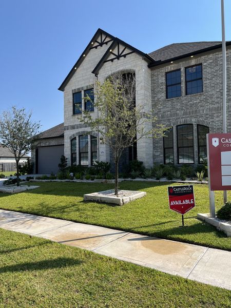 A stunning two-story brick home with a manicured lawn in Marvida by CastleRock Communities (Cypress, TX).
