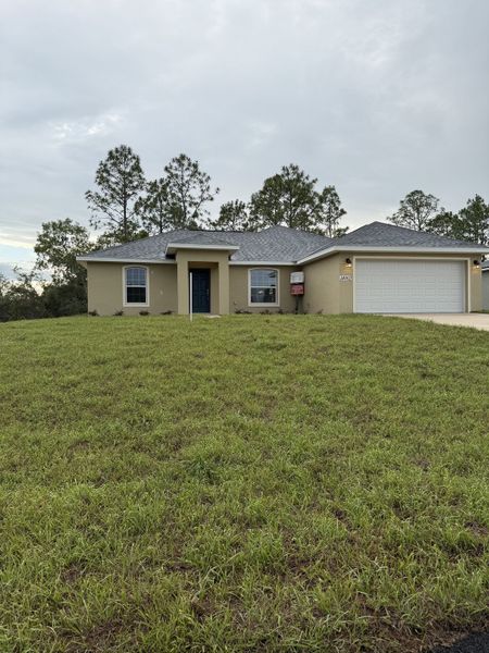 Charming beige home with a spacious green lawn in Marion Oaks by Perfect Deed Homes (Ocala, FL).