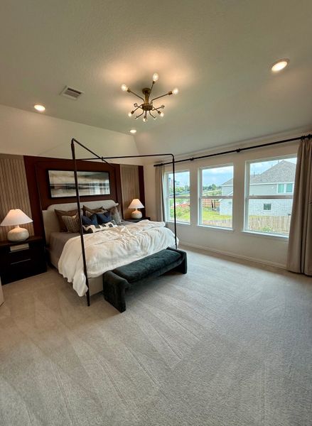 An elegant bedroom with a four-poster bed, plush carpet, and large windows providing ample natural light.