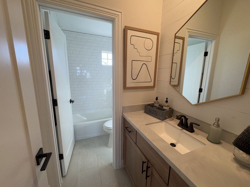 A chic bathroom with a geometric mirror, modern faucet, and minimalist art, featuring a subway-tiled bathtub. A chic bathroom with a geometric mirror, modern faucet, and minimalist art, featuring a subway-tiled bathtub.