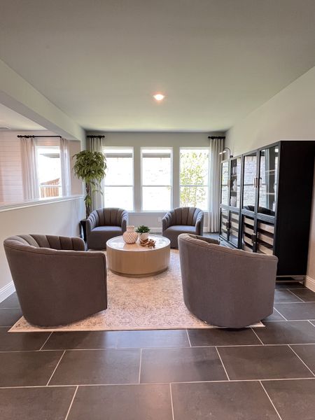 A cozy sitting area with stylish gray swivel chairs, a round coffee table, and natural light through large windows. A cozy sitting area with stylish gray swivel chairs, a round coffee table, and natural light through large windows.