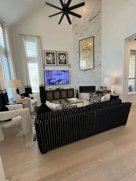 A chic living room with a tall ceiling, marble accent wall, striped sofa, modern decor, and monochrome palette.