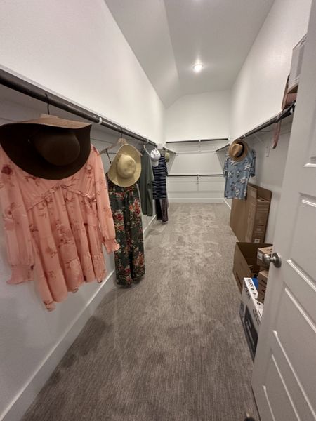 A spacious walk-in closet with carpeted flooring, ample hanging space, and bright overhead lighting. A spacious walk-in closet with carpeted flooring, ample hanging space, and bright overhead lighting.