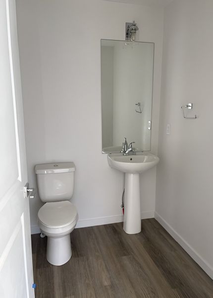 A chic powder bath with a pedestal sink, modern mirror, and elegant lighting.
