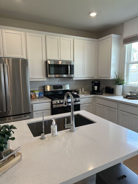 A modern kitchen with sleek white cabinets, stainless steel appliances, and a bright quartz countertop island. A modern kitchen with sleek white cabinets, stainless steel appliances, and a bright quartz countertop island.