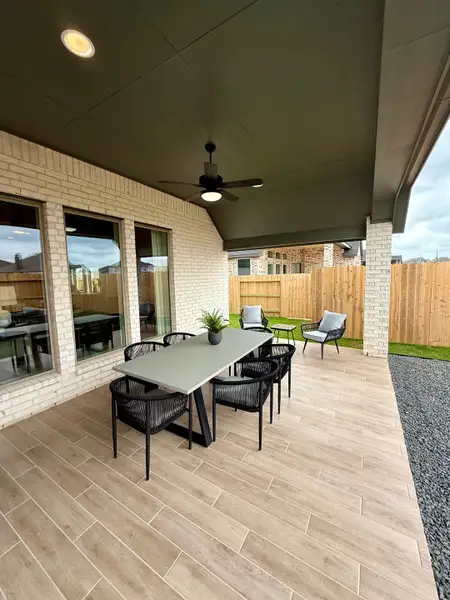 A stylish outdoor patio with wood-look tiles, a sleek dining set, and a modern ceiling fan for relaxation. A stylish outdoor patio with wood-look tiles, a sleek dining set, and a modern ceiling fan for relaxation.