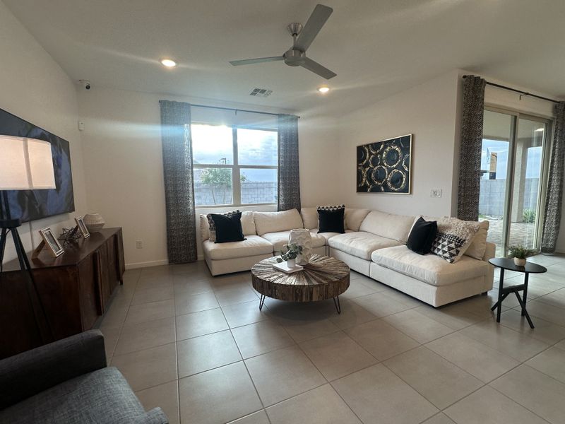 A bright and inviting living room with a large sectional, modern decor, and a ceiling fan for added comfort.