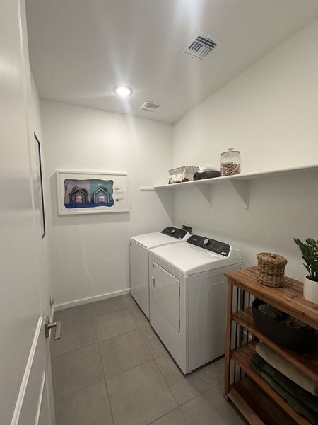 A modern laundry room with white cabinetry, a wooden shelving unit, and efficient washer and dryer setup.