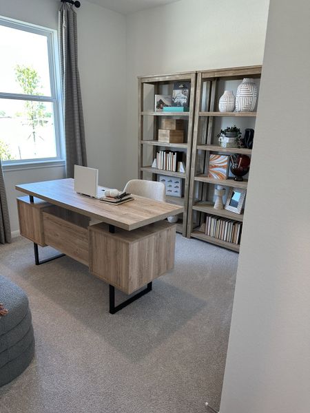 A cozy home office with a modern wooden desk, built-in bookshelves, and soft carpeting. A cozy home office with a modern wooden desk, built-in bookshelves, and soft carpeting.