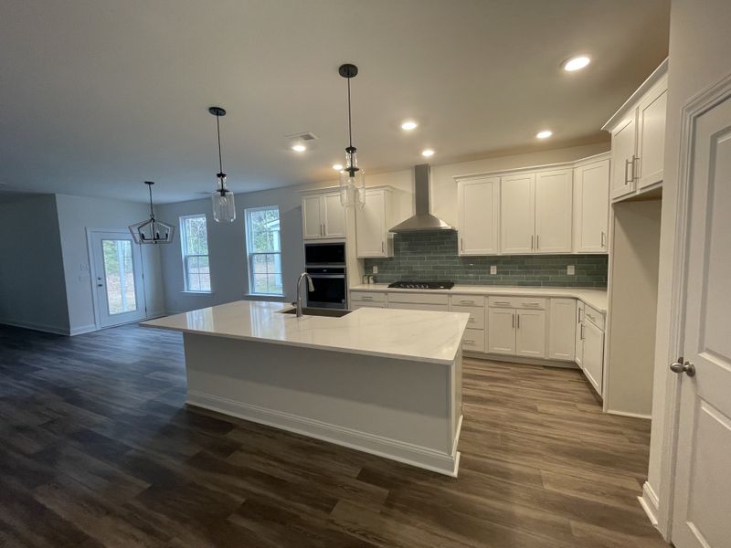 A modern kitchen with sleek white cabinets, a central island, and elegant pendant lighting.