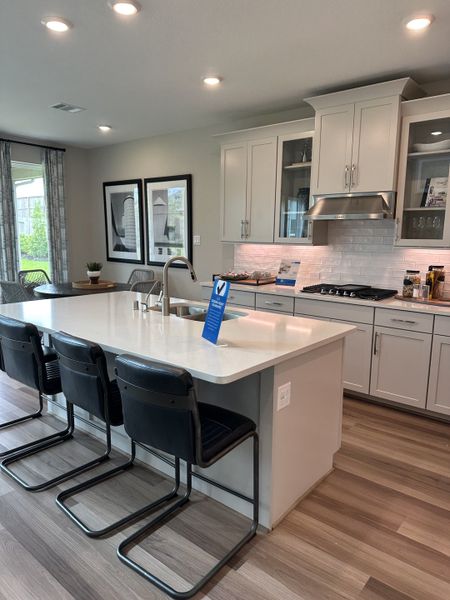 A modern kitchen with a sleek island, black chairs, light cabinetry, and soft lighting, featuring elegant wood flooring. A modern kitchen with a sleek island, black chairs, light cabinetry, and soft lighting, featuring elegant wood flooring.